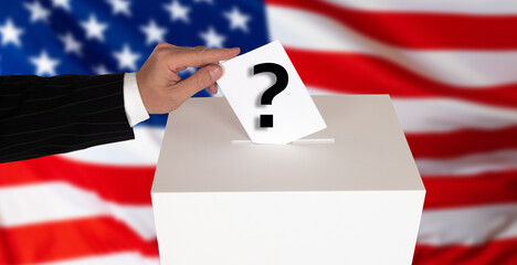 A person puts a ballot with a question mark on the background of the US flag. The intrigue of the...