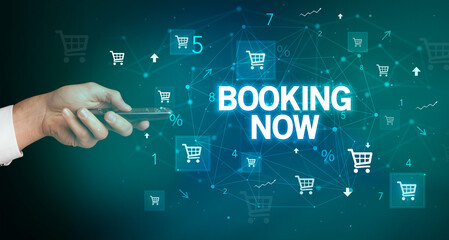 hand holding wireless peripheral with BOOKING NOW inscription, online shopping concept