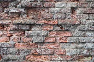 Geometric background made of old bricks. The brick wall is gray-brown. The surface of crumbling bricks.