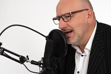 A man with glasses records speech on a microphone. The announcer is broadcasting. Recording a...