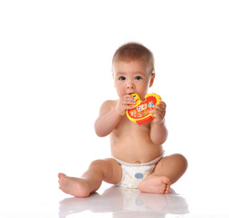 Baby in diaper chewing toy sitting on studio floor