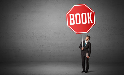Young business person holding road sign with BOOK inscription, new rules concept