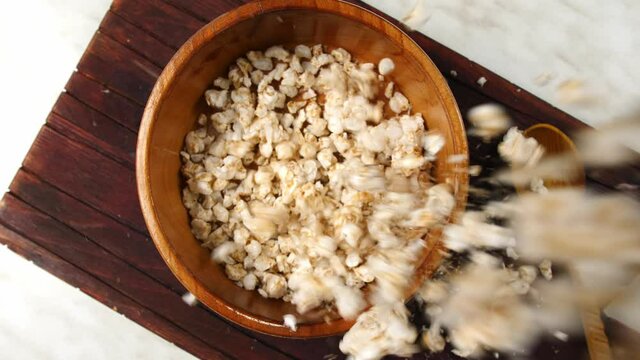 Falling crispy sweet rice in bowl on table, top view