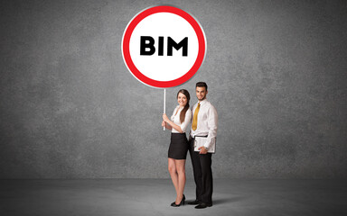 Young business person holdig traffic sign with BIM abbreviation, technology solution concept