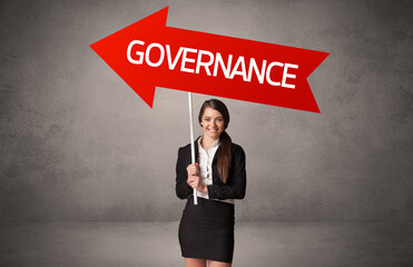 Young business person in casual holding road sign with GOVERNANCE inscription, business direction concept