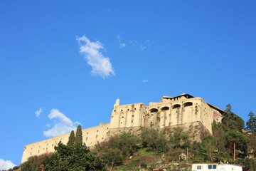 Fototapeta premium ancient ducal fortress perched on a green hill. building overlooking the plain in the blue sky in Tuscany