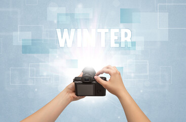 Close-up of a hand holding digital camera with WINTER inscription, traveling concept