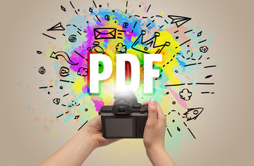 Close-up of a hand holding digital camera with abstract drawing and PDF inscription