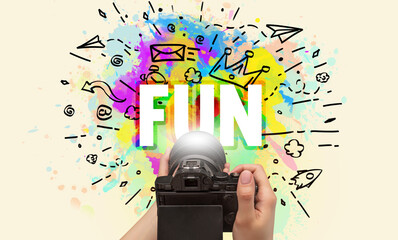Close-up of a hand holding digital camera with abstract drawing and FUN inscription