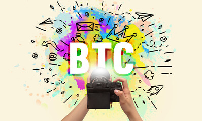 Close-up of a hand holding digital camera with abstract drawing and BTC inscription