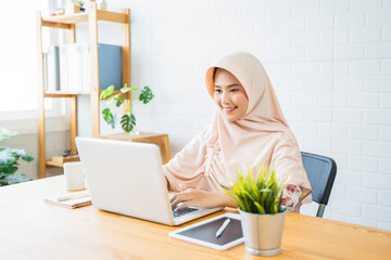 New normal Muslim woman happy smiling working at home business planning innovation ideas researching strategy freelance worker using smart laptop tablet pen device technology, home modern office