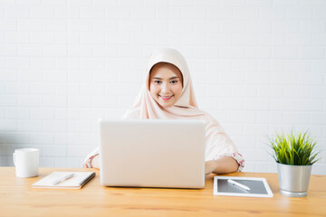 New normal Muslim woman happy smiling working at home business planning innovation ideas researching strategy freelance worker using smart laptop tablet pen device technology, home modern office