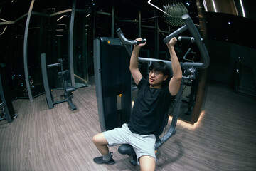 Fototapeta na wymiar ASian male doing exercise for chest muscles on pec deck machine during workout in gym.The sport and healthy lifestyle concept..