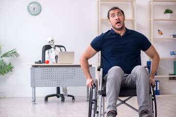 Fototapeta na wymiar Young man in wheel-chair visiting dead doctor