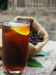 coffee dripping and black ice coffee on wood table with lemon 