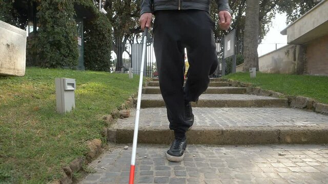 blind man goes down the park stairs with his stick. Orientation, blindness