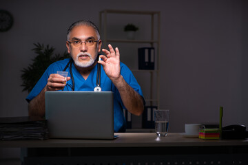 Aged male doctor in the hospital at night