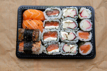 Black tray with hot roll and salmon sushi with cream cheese. Delicious food delivered