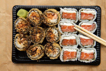 Close up of assorted sushi with chopsticks on the table.