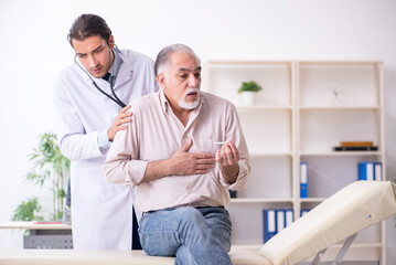 Fototapeta premium Young male doctor and old patient in antismoking concept