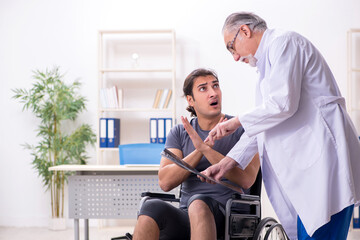 Fototapeta premium Young male patient in wheel-chair visiting old doctor radiologis