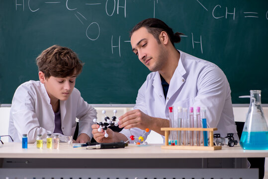 Young chemistry teacher and schoolboy in the classroom