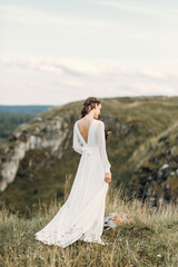 Bride with a bouquet of dried flowers walking in nature. Boho style wedding in autumn.