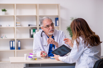 Obraz premium Old male doctor radiologist and his young female assistant in th