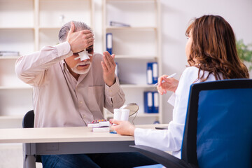 Naklejka premium Old man visiting young female doctor for plastic surgery