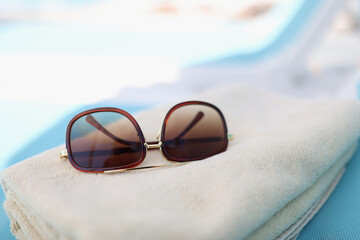 Fototapeta na wymiar Sunglasses lie on towel on beach. Sale of travel tours to warm countries concept.