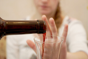     Wine is poured from a bottle into a glass, and the young girl refuses it with a gesture.