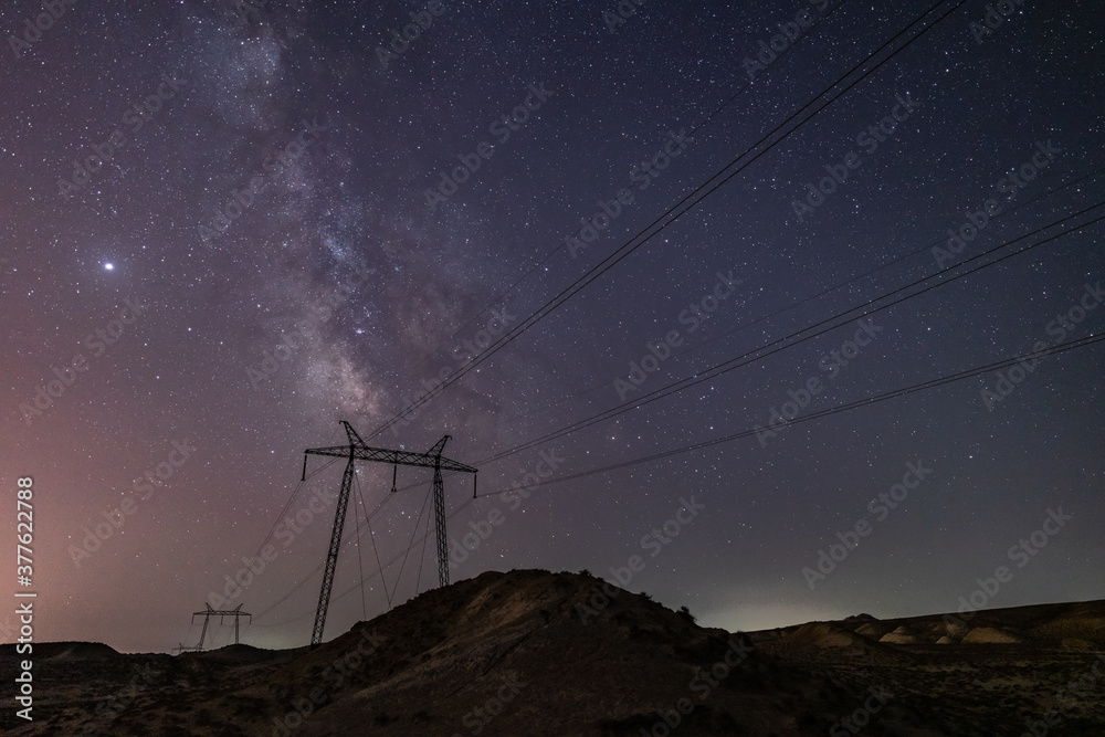 Wall mural milky way galaxy in the night sky above power line supports