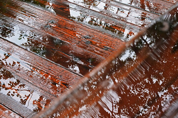 雨に濡れた木製の手すりと木の床の水に映る樹木のシルエット