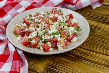 Tasty salad of tomato, cottage cheese, dill and olive oil on wooden table