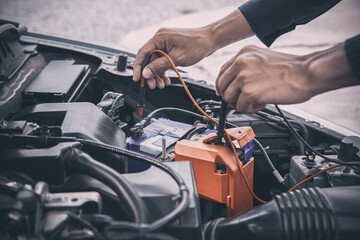 Auto mechanic are using measuring equipment tool for checking car battery. Concepts of Old car fix repair and service insurance.
