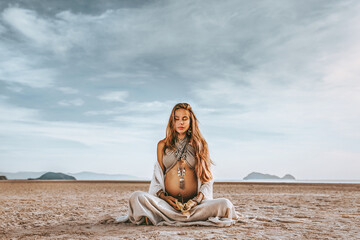 beautiful young stylish pregnant woman with boho accessories on the beach at sunset - 377623763