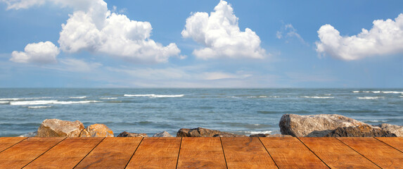 Wooden floor for the beach walkway with a rocky sea background blue sky and cloud.