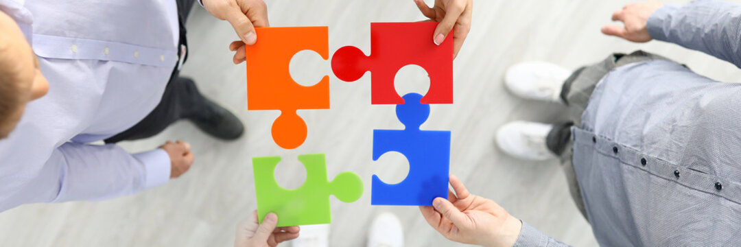 Group businees people hold color element puzzle top view background closeup. Each fulfills its task division of labor concept