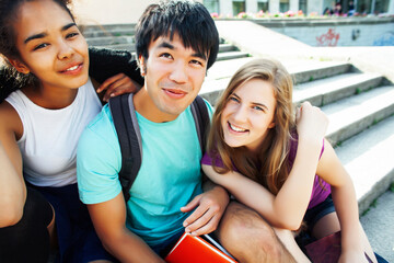 cute group of teenages at the building of university with books huggings, diversity nations, having lunch
