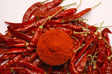 Dried red chili powder with red chili in a bowl in white background