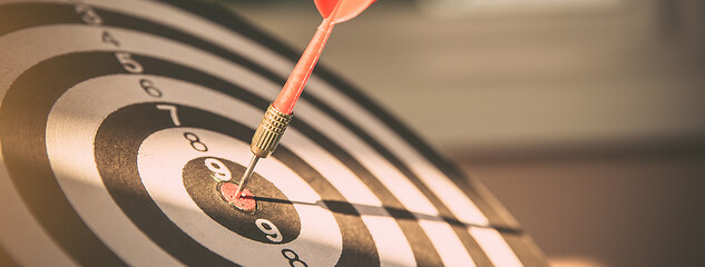 Bulls eye or dart board has red dart arrow throw hitting the center of a shooting target for...