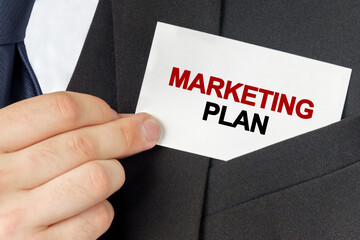 Businessman holds a card with the text - MARKETING PLAN