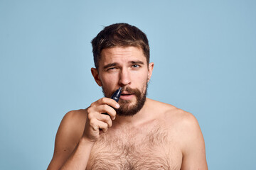 Fototapeta premium man with bare shoulders removes nose hair hygiene care blue background