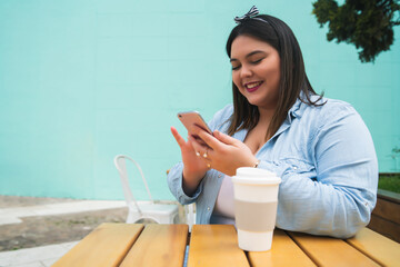 Young plus size woman using phone at coffee shop.