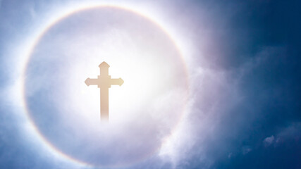 Silhouette of cross at with solar reflection and blue sky holy light.
