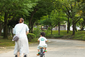 公園を自転車とベビーカーで散歩する日本人の親子