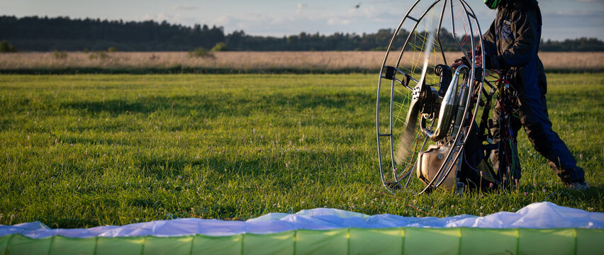 The pilot is preparing for flights a personal paralet with a gasoline engine. Paragliding for individual paragliding flights. Preparation for wing flight. Extreme sports. Small aircraft. Wide view