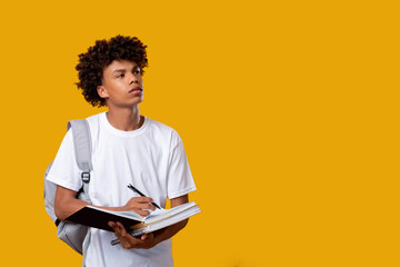 Doubtful black teenager. Think idea. Puzzled african male student writing in notebook isolated on...