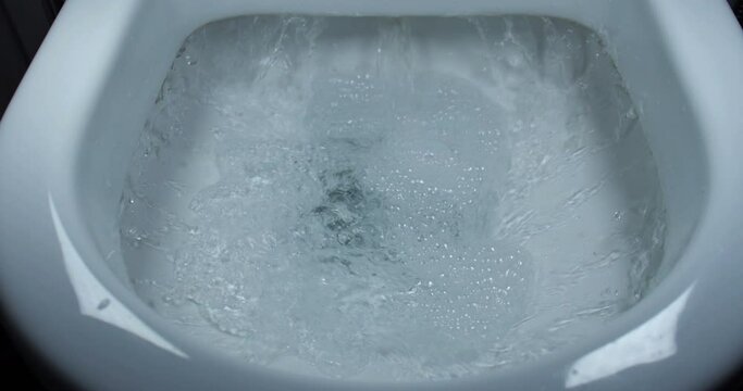 the toilet is light in color, the water is flushed,slow motion