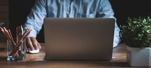 Concentrated young businessman working on a laptop while sitting at the wooden table  Stay at home concept.